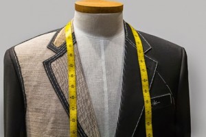 Unfinished black jacket with white thread stitches and yellow measuring tape